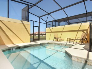 An indoor swimming pool with clear glass walls, a 3 ft depth marker, and lounge chairs.