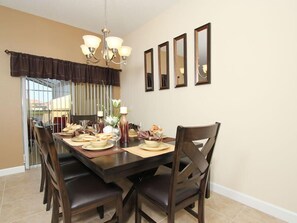 A dining area with a large table, multiple chairs, a chandelier, and wall-mounted mirrors.