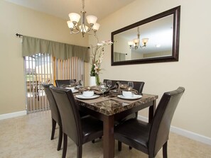 A dining area with a marble table, black chairs, a chandelier, and a large mirror on the wall. - Ov2899 - Paradise Palms - 4 Bed 3 Baths Townhome (Kissimmee)