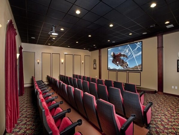 A conference room with rows of red and black chairs, a large screen displaying a space-themed image, and a patterned carpet. - Ov2899 - Paradise Palms - 4 Bed 3 Baths Townhome (Kissimmee)