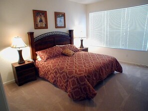 A bedroom with a large bed, two nightstands, two lamps, a window with blinds, and two framed pictures on the wall. - Ov2935 - Windsor Hills Resort - 5 Bed 5 Baths Villa (Kissimmee)