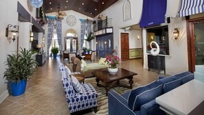 A spacious lobby with a high ceiling, wooden beams, and a central seating area with sofas and a coffee table.