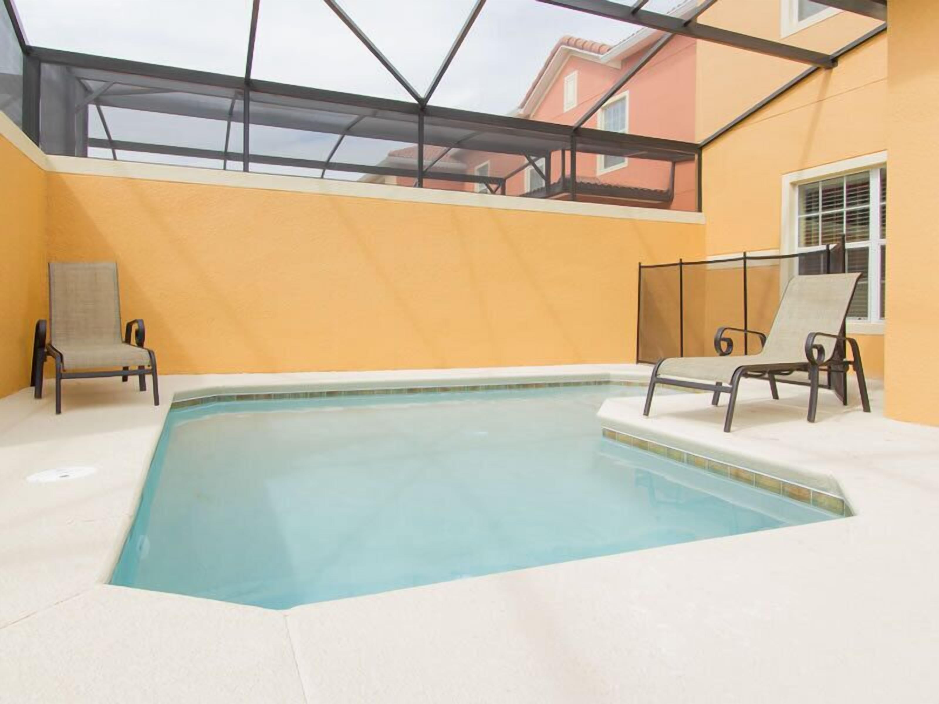 An indoor swimming pool with two lounge chairs and a glass ceiling.