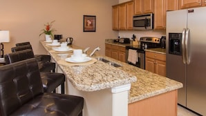 A modern kitchen with granite countertops, stainless steel appliances, and wooden cabinets.