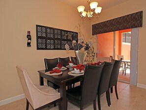 A dining area with a dark wooden table, six chairs, and a decorative wall piece above.