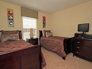 A bedroom with two beds, a dresser, a television, and decorative wall art.