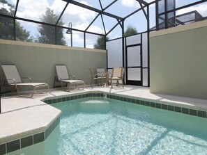 A swimming pool with lounge chairs and a glass ceiling structure.