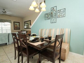 A dining area with a wooden table and chairs, a striped bench, and wall art.