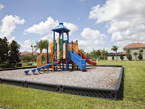 Explore the vibrant playground with slides and climbing elements set amidst a lush green area.