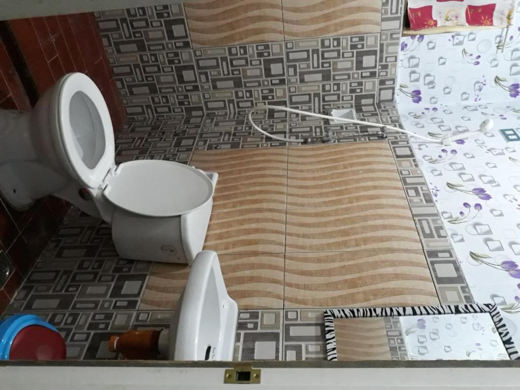 Et badeværelse med toilet, gulvfliser med mønster og et delvist synligt bruseområde.