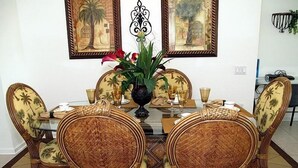 A dining area with a round table, wicker chairs, and a vase with flowers. - Ov2608 - Windsor Hills Resort - 5 Bed 5 Baths Villa (Kissimmee)