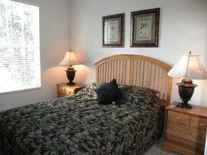 A bedroom with a bed, two nightstands, a window with blinds, and two framed pictures on the wall. - Ov2762 - Trafalgar Village Resort - 4 Bed 4 Baths Villa (Kissimmee)