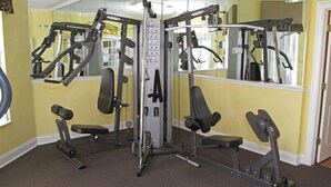 A home gym with a mirrored wall, weight machines, and a bench. - Ov2644 - Emerald Island - 3 Bed 2.5 Baths Townhome (Kissimmee)