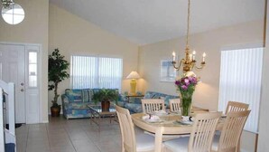 A dining area with a round table, chairs, a chandelier, and a sofa in the background. - Ov2682 - Espirit - 4 Bed 2.5 Baths Villa (Davenport)