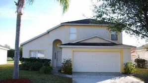 A single-story house with a garage, a front yard with a palm tree, and a small garden area. - Ov2682 - Espirit - 4 Bed 2.5 Baths Villa (Davenport)