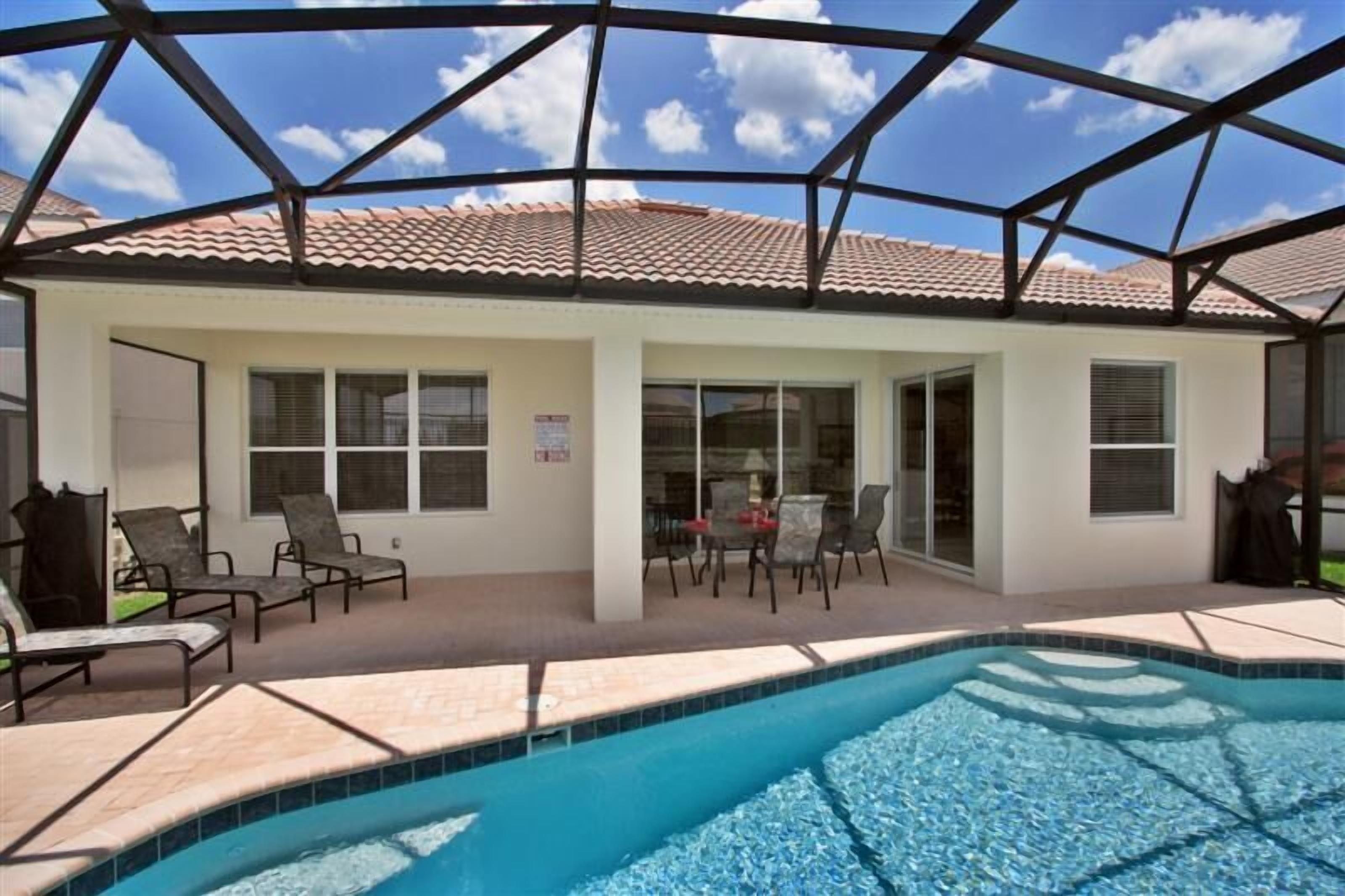 Uma área de piscina ao ar livre coberta, com espreguiçadeiras e uma mesa de pátio.