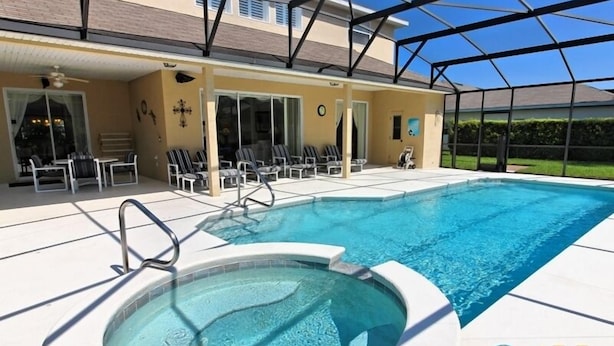 Ein Schwimmbecken mit Whirlpool, Liegestühlen und einer überdachten Terrasse.