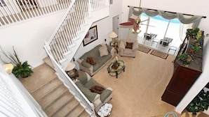 Ein geräumiger Wohnbereich mit Treppe, einer Sofagarnitur, einem Couchtisch und Blick ins Freie.