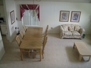 A dining area with a wooden table and chairs, a floral sofa, and a bench. - Ov2648 - Oak Island Harbour - 4 Bed 2.5 Baths Villa (Kissimmee)
