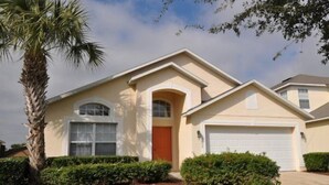 A two-story house with a beige exterior, a red door, and a white garage door.