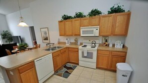A modern kitchen with wooden cabinets, a white microwave, a stove, and a dishwasher.