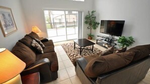 A living room with a sofa, a coffee table, a TV, and a lamp.
