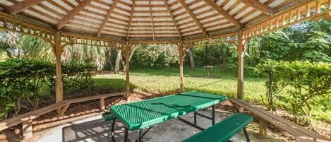 A gazebo with a wooden roof and a picnic table.