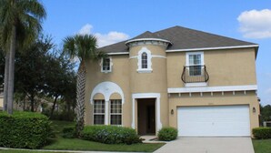A two-story house with a curved facade, a front garage, and a small balcony. - Ov2182 - Emerald Island - 7 Bed 5.5 Baths Villa (Kissimmee)