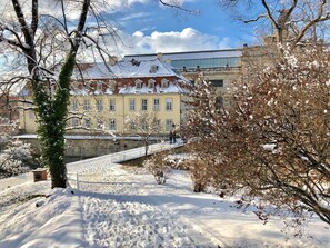 A snow-covered courtyard with a building featuring multiple windows and a traditional roof.