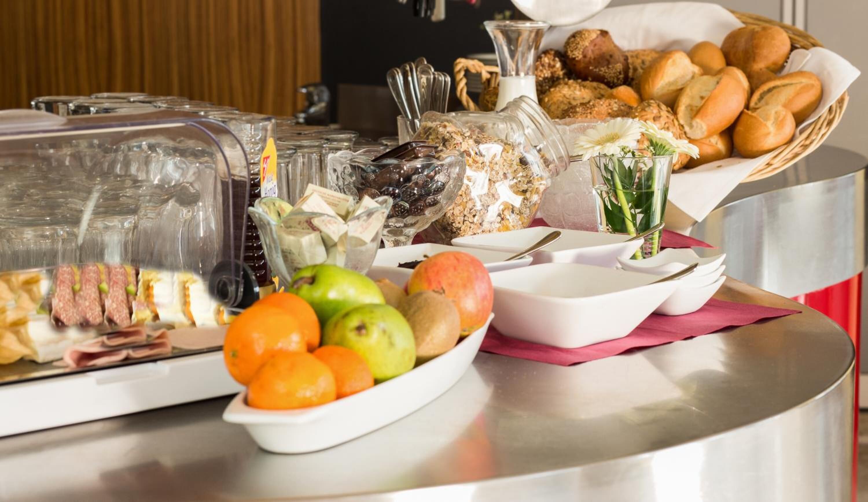 A buffet with various food items including fruits, bread, and pastries.