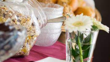 A breakfast buffet with various food items and a glass vase with flowers.