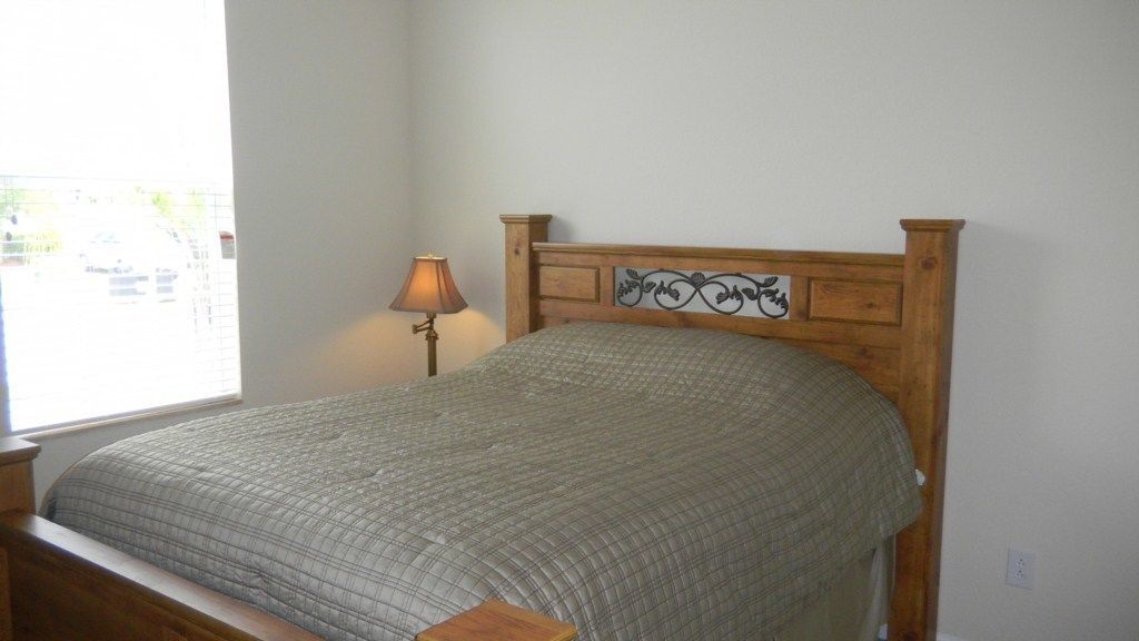 A single bed with a wooden headboard and a bedside lamp.