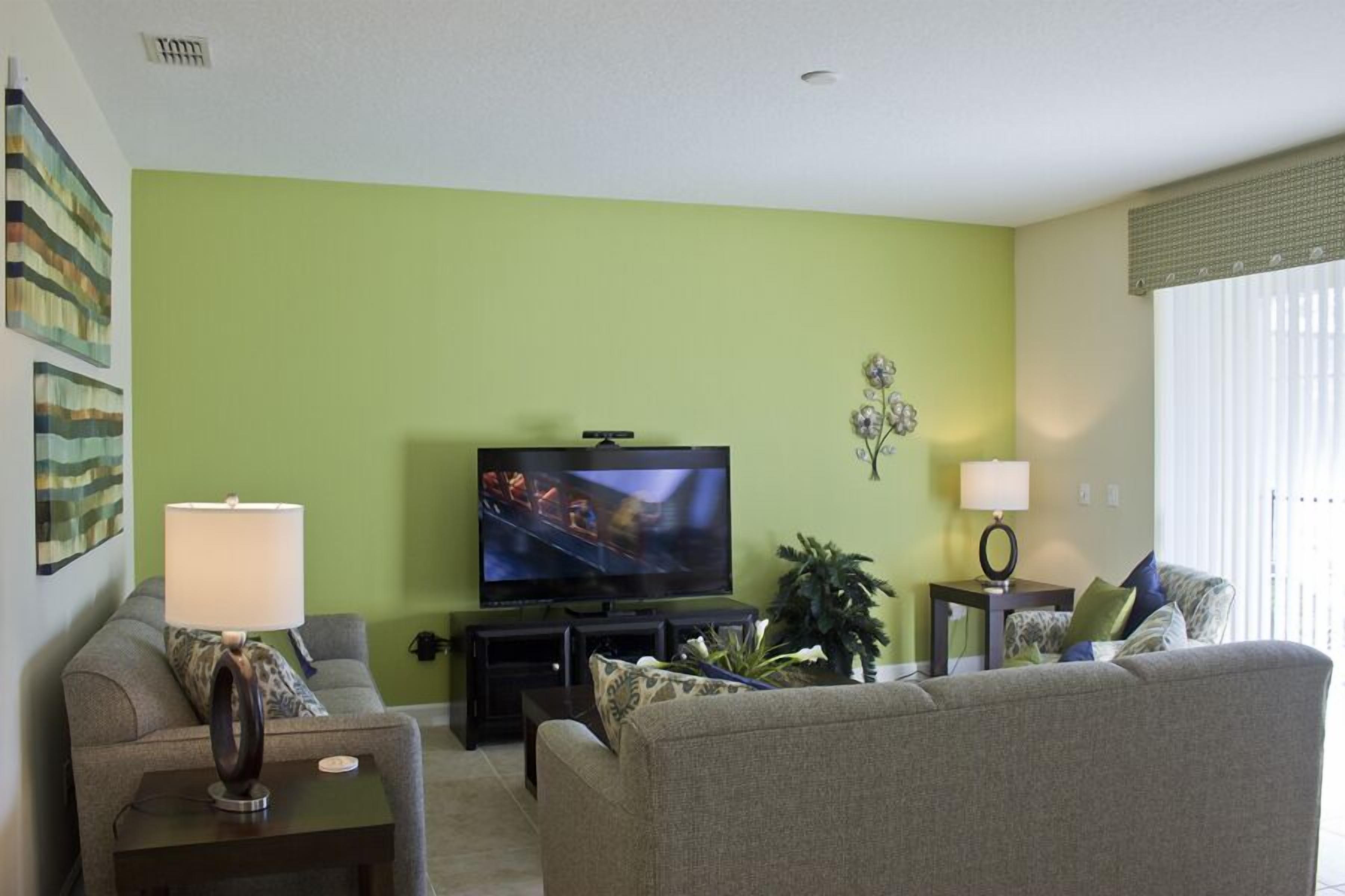 A living room with a television, two sofas, a coffee table, a lamp, and a plant.