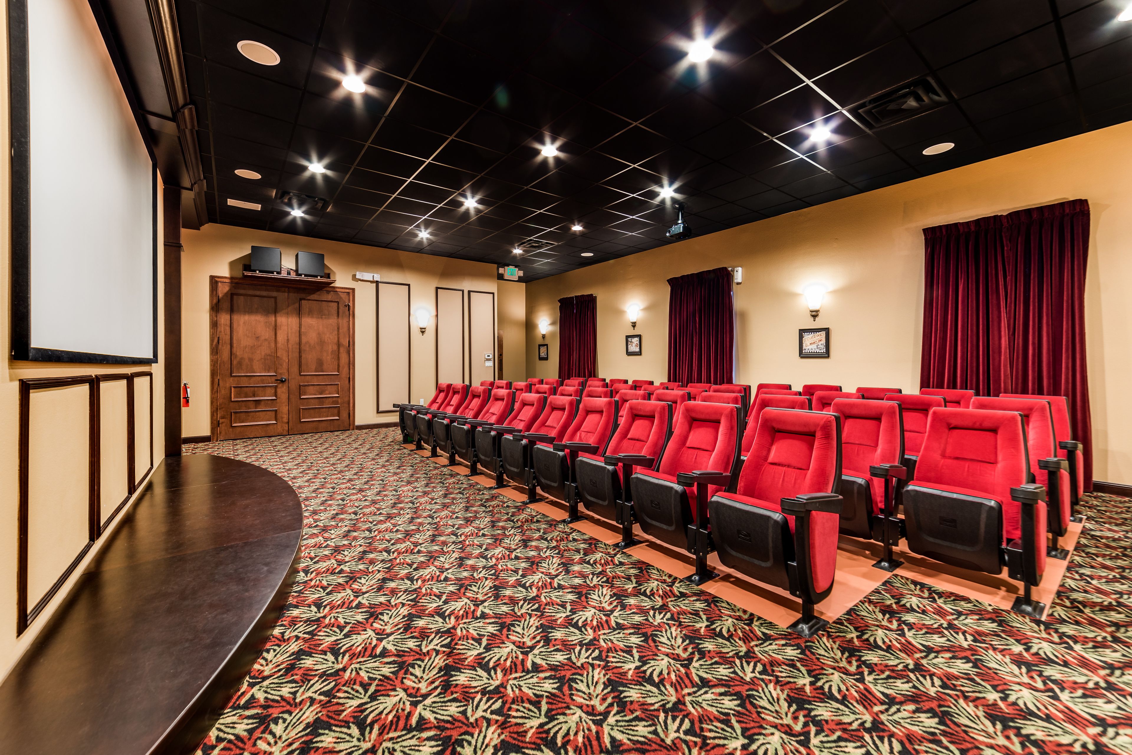 A theater with rows of red seats, a stage, and a patterned carpet.