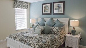 A bedroom with a patterned bedspread, two bedside lamps, a nightstand with a vase, and two framed pictures on the wall. - Ov2668 - Paradise Palms - 6 Bed 5 Baths Villa (Kissimmee)