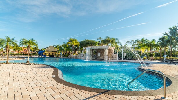 A swimming pool with a waterfall feature, surrounded by palm trees and a brick walkway. - Ov2668 - Paradise Palms - 6 Bed 5 Baths Villa (Kissimmee)