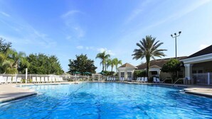 A clear blue swimming pool with lounge chairs and umbrellas, surrounded by palm trees and a building with a covered patio. - Ov2587 - Windsor Palms Resort - 4 Bed 3 Baths Townhome (Kissimmee)