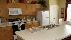 A kitchen with wooden cabinets, a microwave, stove, refrigerator, and a sink. - Ov2562 - Windsor Palms Resort - 4 Bed 3 Baths Townhome (Kissimmee)