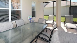 A covered patio with a glass-top table and chairs, large windows, and a basketball hoop. - Ov2542 - Windsor Hills Resort - 6 Bed 4 Baths Villa (Kissimmee)