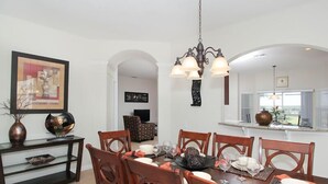 A dining area with a wooden table and chairs, a chandelier, and a view of the kitchen through an archway. - Ov2542 - Windsor Hills Resort - 6 Bed 4 Baths Villa (Kissimmee)