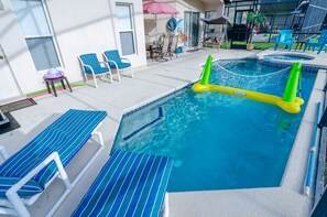 Ett poolområde med blårandiga solstolar, ett litet bord och en bubbelpool.