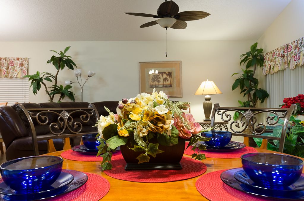 A dining area with a wooden table, blue glass bowls, and a floral centerpiece.