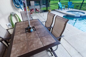 En uteplats med ett bord och stolar, ett bubbelbad och en pool.