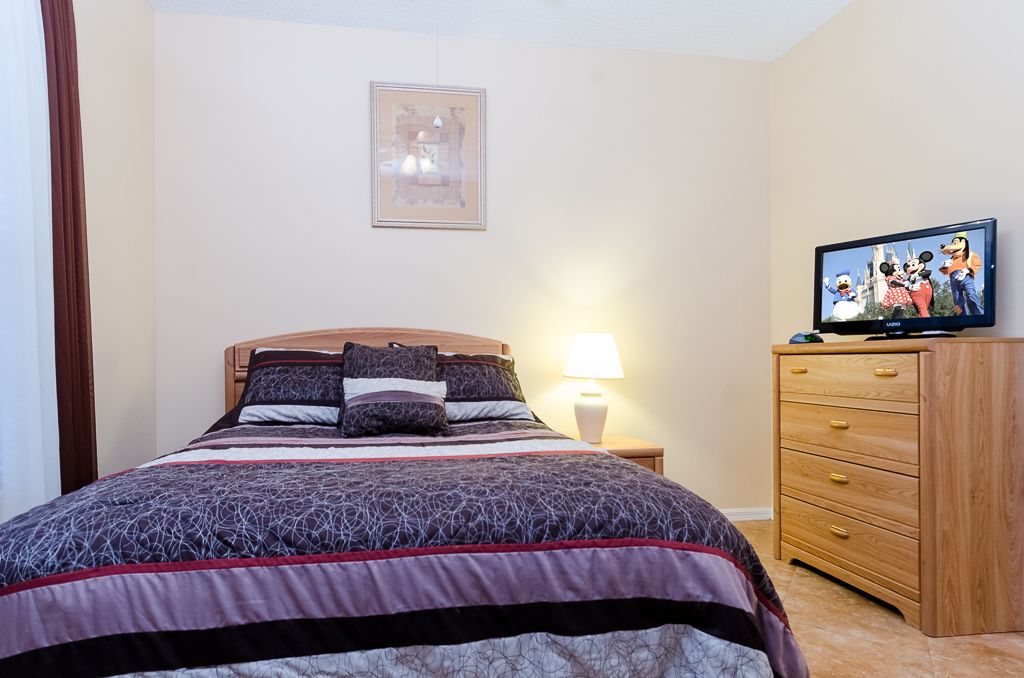 A bedroom with a bed, a TV, a nightstand, and a dresser.