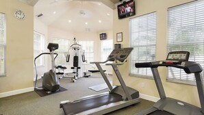 Ett gym med löpband, styrketräningsmaskiner och en tv-skärm.