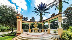 Una fuente circular con escalones que la rodean, en un jardín bien cuidado, y un cartel que dice 'WERSONG'.