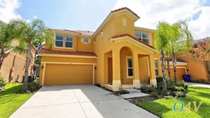 A yellow two-story house with a red-tiled roof, a garage, and a front porch with columns. - Ov2465 - Bella Vida Resort - 6 Bed 5.5 Baths Villa (Kissimmee)