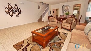 A living room with a coffee table, two armchairs, a sofa, a staircase, and a dining area. - Ov2465 - Bella Vida Resort - 6 Bed 5.5 Baths Villa (Kissimmee)