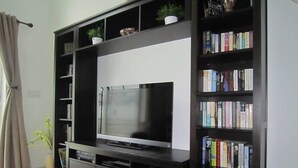 Un salon doté d’un grand téléviseur à écran plat posé sur un meuble noir, l’ensemble étant entouré d’étagères remplies de livres.