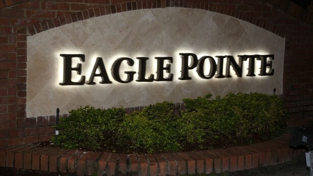 Une enseigne portant le nom « Eagle Pointe » est illuminée sur un mur de briques.